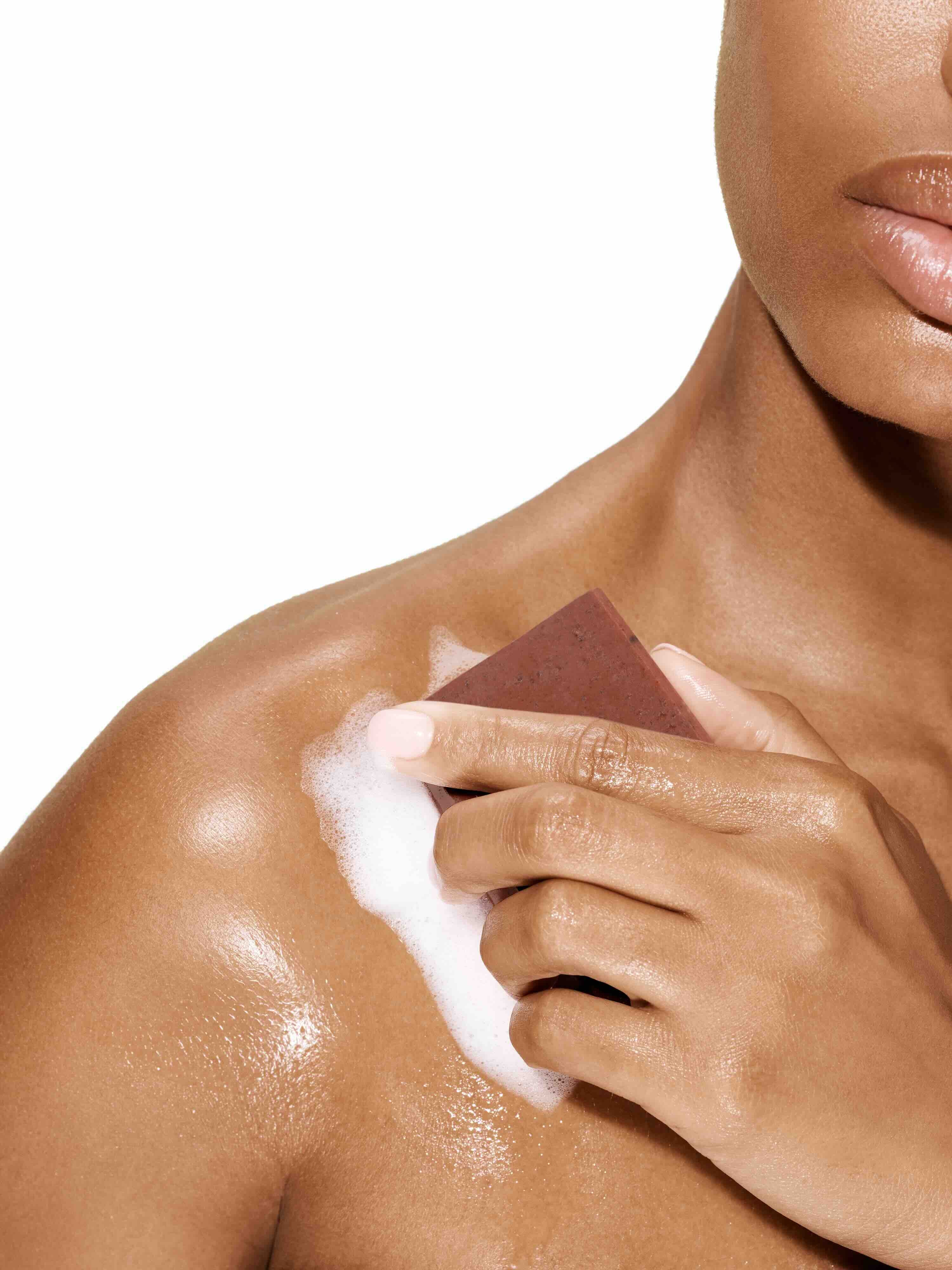 Image of a female model using a bar of Antü Restoring Soap on her shoulder.